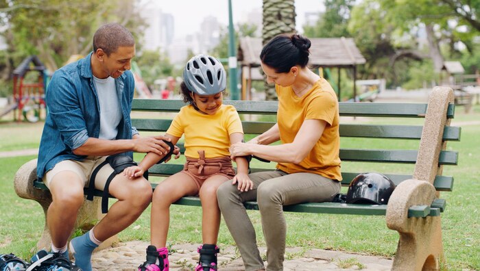 parents-park-bench-helmet-with-kid-help-safety-skating-rollerskate-bike-interracial-family-mom-dad-with-helping-hand-teaching-girl-kid-bonding-learning-exercise_590464-149754